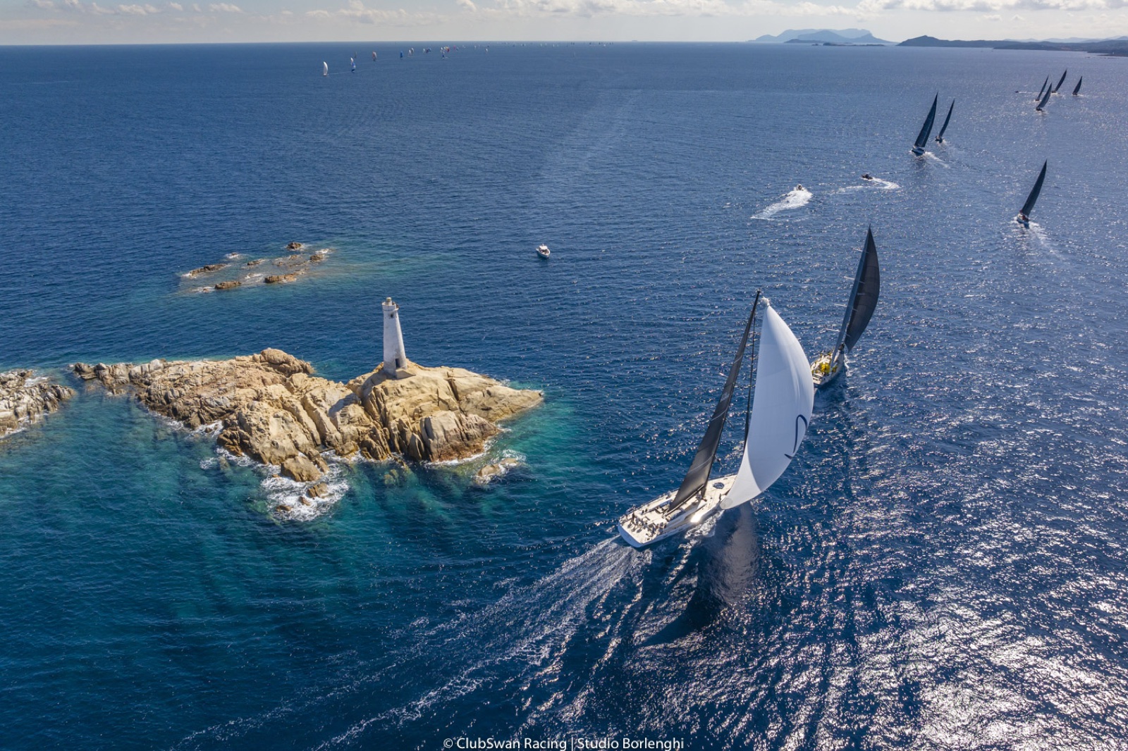 Un velero Swan bordeando el faro de un islote rocoso en Cerdeña. Foto: Studio Borlenghi / ClubSwan Racing